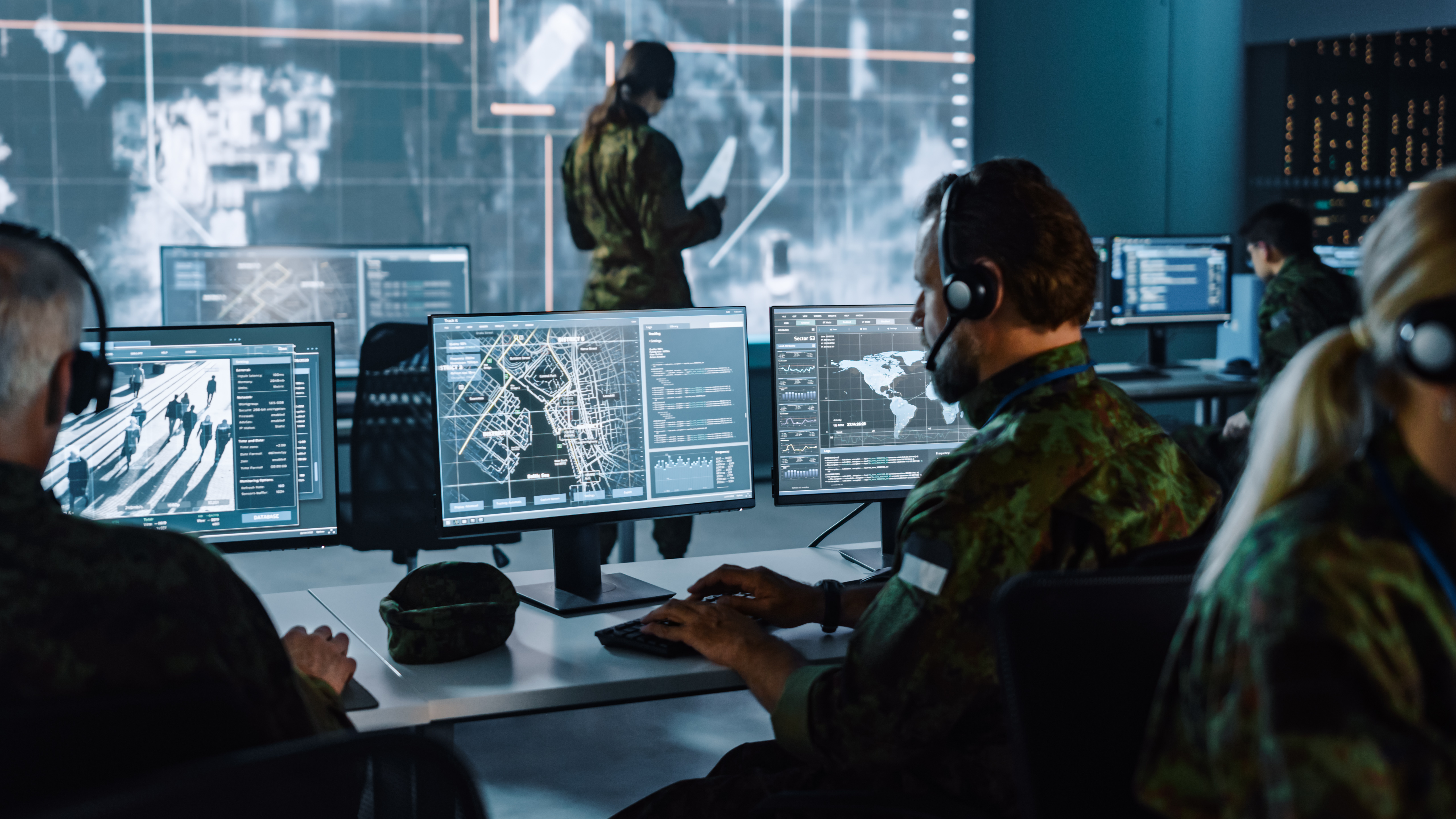 military personnel in control room with computer monitors 